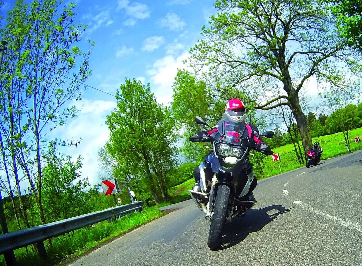 Motorrad in Schräglage auf einer von Bäumen gesäumten Straße Motorrad in Schräglage auf einer von Bäumen gesäumten Straße